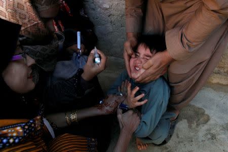A boy reacts as he is being administered polio vaccine drops by anti-polio vaccination workers along a street in Quetta, Pakistan January 2, 2017. REUTERS/Naseer Ahmed