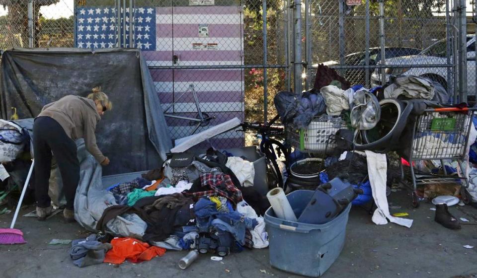 A woman camping in downtown San Diego sorts through her belongings in 2017. Homeless residents of downtown San Diego encampments will be paid to pick up trash in their neighborhood as part of a new pilot program. Gregory Bull/AP file