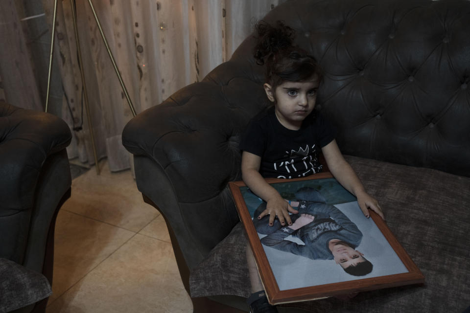 Sham Manasra holds a portrait of her older brother Ahmad Manasra, who has been imprisoned by Israel since he was 13 when he was was convicted of attempted murder and sentenced to nine and a half years in prison, after his older cousin stabbed two Israelis, in their family home in east Jerusalem, Tuesday, Nov. 8, 2022. The 13 year-old Palestinian boy, whose case became a lighting rod for the Israeli-Palestinian conflict seven years ago, is now a man languishing in solitary confinement and struggling with schizophrenia. This week, Israel's Supreme Court will decide on an appeal for his early release. (AP Photo/ Maya Alleruzzo)