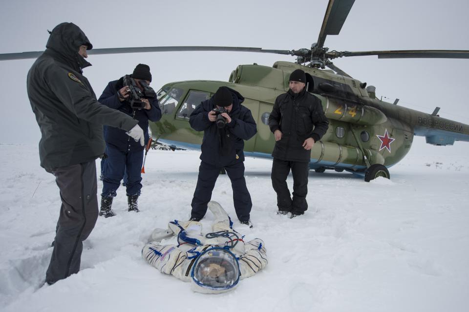 A photographer and an operator document the suit worn byAstronaut Michael Hopkins from NASA after the landing of the Soyuz TMA-10M capsule in a remote area southeast of the town of Zhezkazgan in central Kazakhstan, March 11, 2014. (REUTERS/Bill Ingalls/NASA/Handout via Reuters)