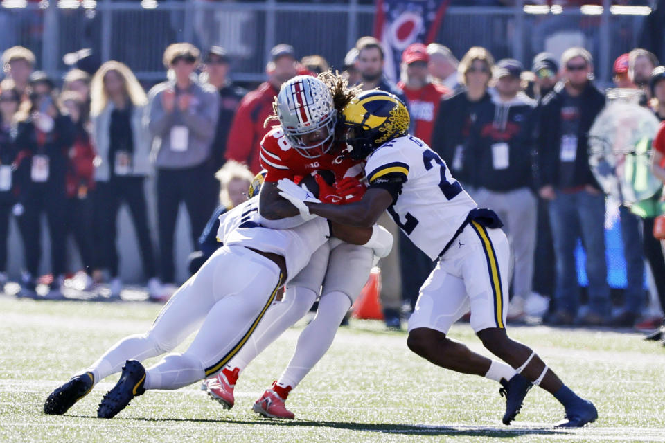 Michigan defensive back R.J. Moten, left, and defensive back Gemon Green tackle Ohio State tight end Gee Scott during the first half of an NCAA college football game on Saturday, Nov. 26, 2022, in Columbus, Ohio. (AP Photo/Jay LaPrete)