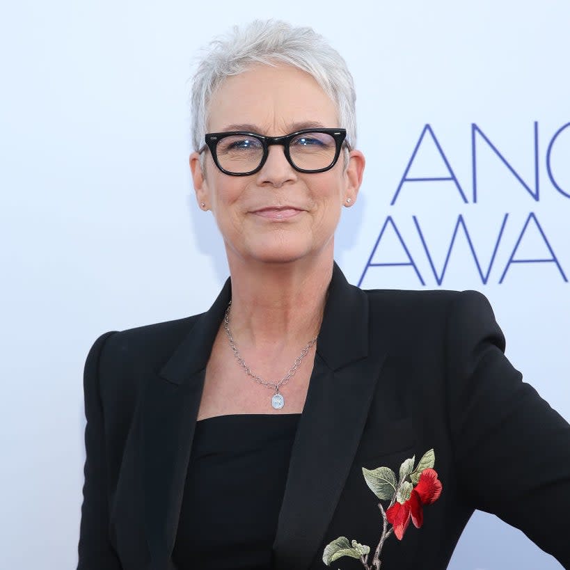 Jamie Lee Curtis at event, wearing a black suit with floral embroidery, glasses