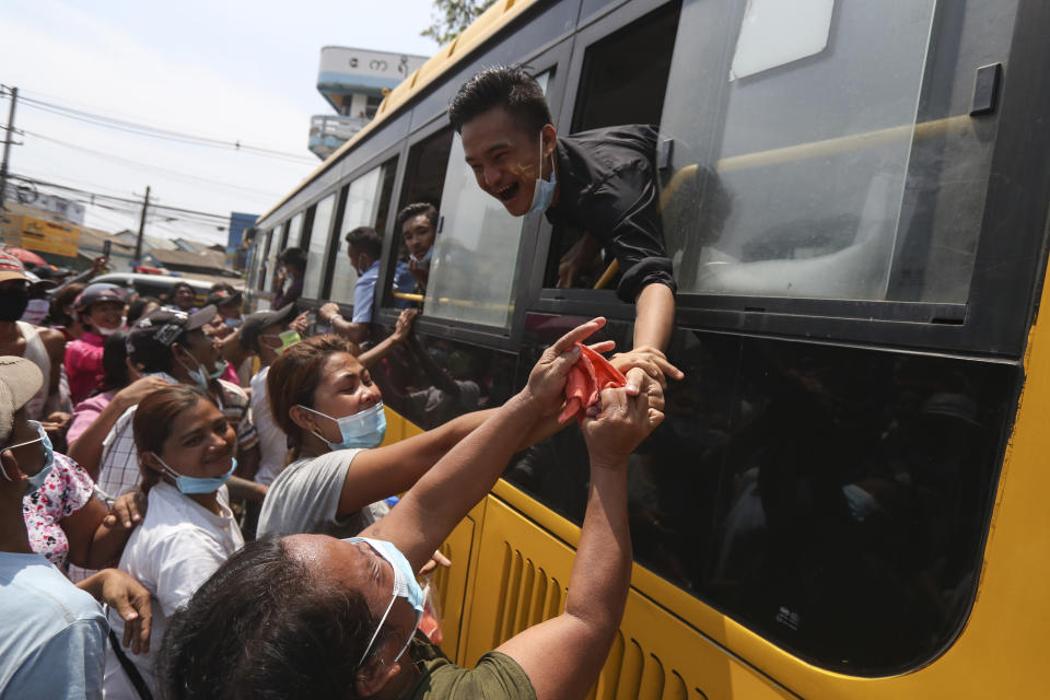 A prisoner reaches out from a bus to shake hands with family members after being released from the Insein prison during a presidential pardon in Yangon, Myanmar, Friday, April 17, 2020. Myanmar says it is releasing almost 25,000 prisoners under a presidential amnesty marking this week's traditional Lunar New Year celebration. (AP Photo/Thein Zaw)