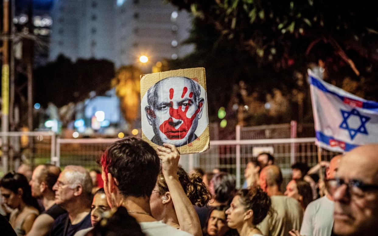 An Israeli Protestor holds up a placard showing the face of Benjamin Netanyahu, the Israeli prime minister, during a demonstration