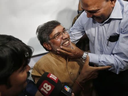 Children's right activist Kailash Satyarthi (C) is congratulated by an unidentified man at his office in New Delhi October 10, 2014. REUTERS/Adnan Abidi