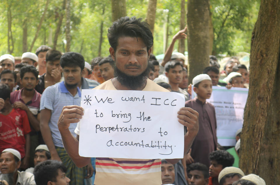 A Rohingya refugee holds a placards during a gathering to mark the fifth anniversary of their exodus from Myanmar to Bangladesh, at a Kutupalong Rohingya refugee camp at Ukhiya in Cox's Bazar district, Bangladesh, Thursday, Aug. 25, 2022. Hundreds of thousands of Rohingya refugees on Thursday marked the fifth anniversary of their exodus from Myanmar to Bangladesh, while the United States, European Union and other Western nations pledged to continue supporting the refugees' pursuit of justice in international courts.(AP Photo/ Shafiqur Rahman)