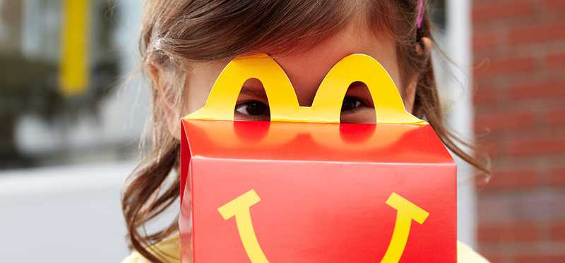 A child looks through the top of a happy meal box.