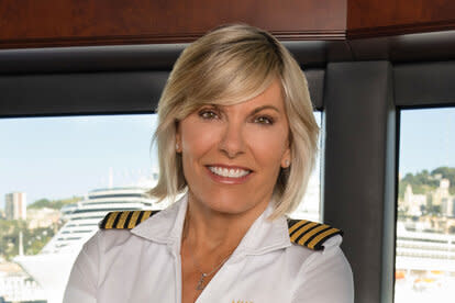 Captain Sandy smiling with her arms crossed in the wheelhouse of the yacht.