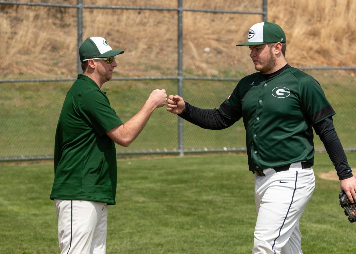 Grafton High School assistant baseball coach Dave Wooten greets pitcher James Tindall during a game against Clinton High School.