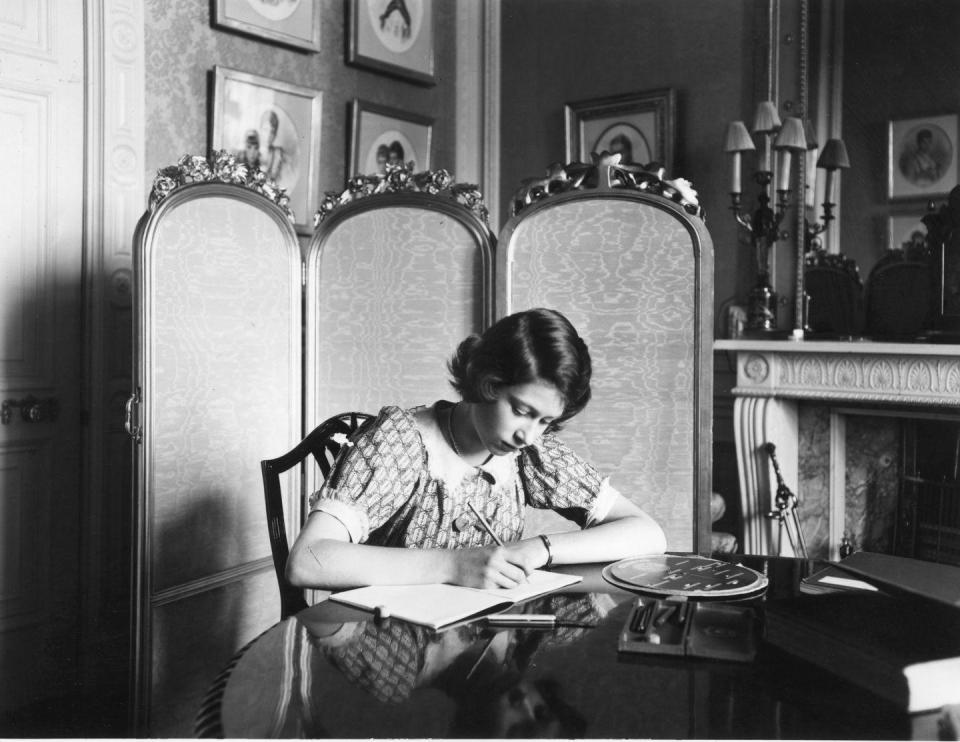 <p>Seated at a writing desk in Windsor Castle, a young Princess Elizabeth is photographed working on her studies in 1940. </p>