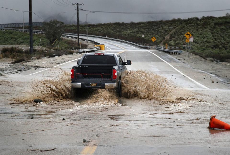 A driver disobeys road closure signs and drives through the flooded Glen Helen Parkway during Tuesday's storm in Devore.