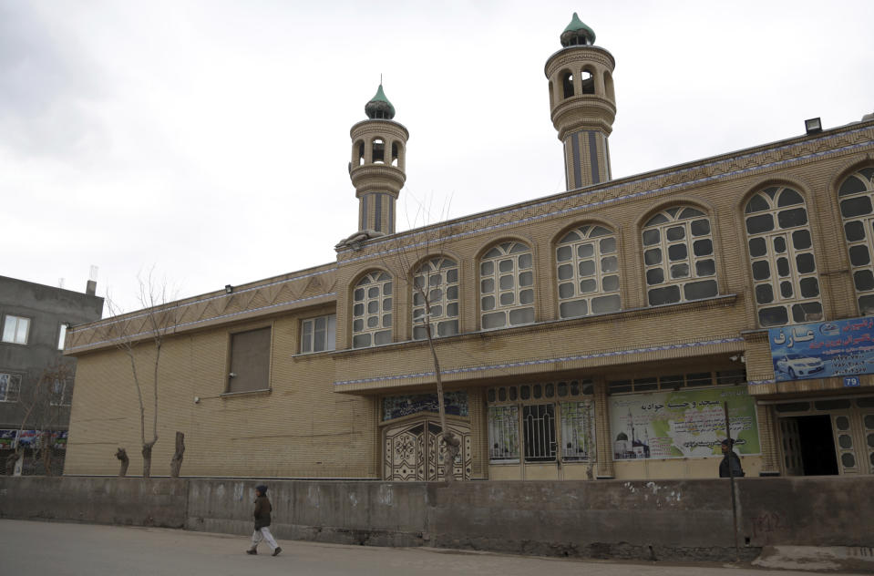 In this Feb. 20, 2019 photo, an Afghan boy walks past the Jawadia Shiite mosque that was targeted by by Islamic State gunmen last May, killing 38 people, in Herat, western Afghanistan. Afghan veterans returning from Syria are threatened from multiple sides. They face arrest by security agencies that view them as traitors. And they face violence from the brutal IS in Afghanistan, which views Shiites as heretics and vows to kill them. (AP Photo/Rahmat Gul)