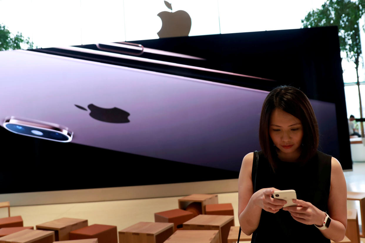 FILE PHOTO: A woman checks her phone at a flagship Apple store at Iconsiam shopping mall in Bangkok, Thailand November 9, 2018. REUTERS/Soe Zeya Tun/File Photo