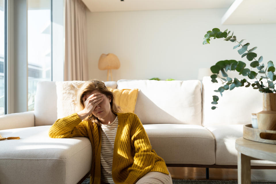 Woman suffering headache holding her head at home