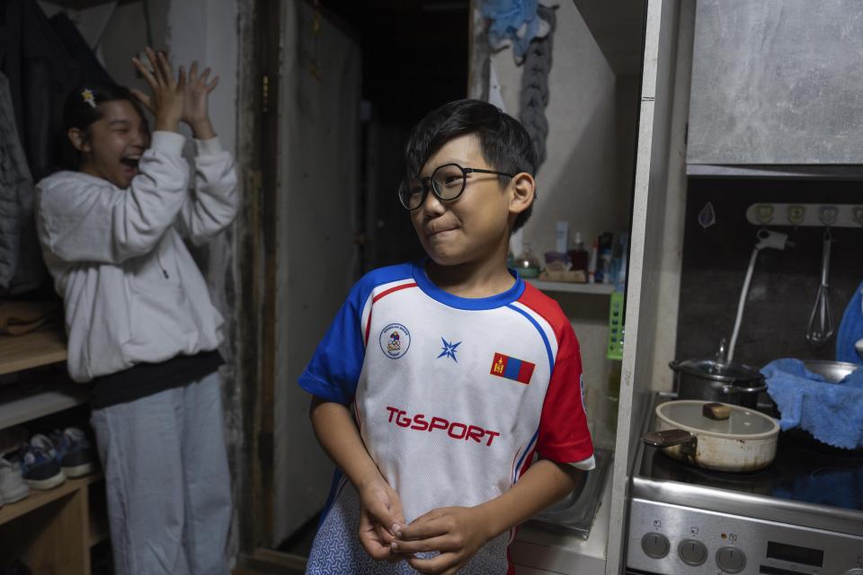 Twelve-year-old Gerelt-Od Kherlen looks on as his older sister Solongo Kherlen, left, reacts in their home in a Ger district on the outskirts of Ulaanbaatar, Mongolia, Tuesday, July 2, 2024. Growing up in a Ger district without proper running water, Gerelt-Od fetched water from a nearby kiosk every day for his family. Carrying water and playing ball with his siblings and other children made him strong and resilient. (AP Photo/Ng Han Guan)