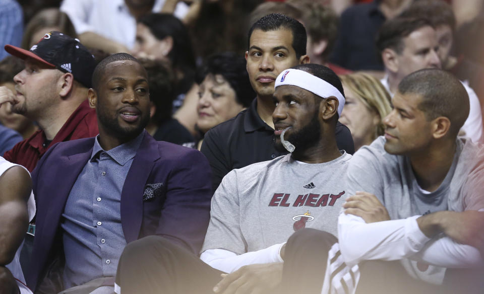 Miami Heat players Dwyane Wade, left, talks to LeBron James, and Shane Battier during the first half of an NBA basketball game in Miami, Monday, March 3, 2014 against the Charlotte Bobcats. Wade did not play in the game. (AP Photo/J Pat Carter)