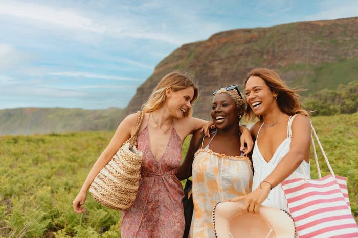 group of three smiling friends walking hand in hand and happy on the beach during a vacation trip