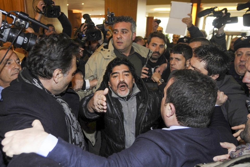 FILE - Diego Armando Maradona makes his way through journalists as he arrives in Naples, Italy, Feb. 25, 2013. The legend of Diego Maradona at Napoli hovers over the current team’s Italian league title, which was sealed Thursday, May 4, 2023 . The Argentina standout holds saint-like status in Naples 2 ½ years after his death and more than three decades after he led Napoli to its first two Serie A titles. (AP Photo/Salvatore Laporta, File)