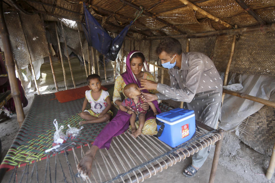 A health worker gives a polio vaccine to a child at a slum area in Lahore, Pakistan, Saturday, Aug. 15, 2020. Pakistani government launched an anti-polio vaccination campaign in an effort to eradicate the crippling disease affected children. (AP Photo/K.M. Chaudary)