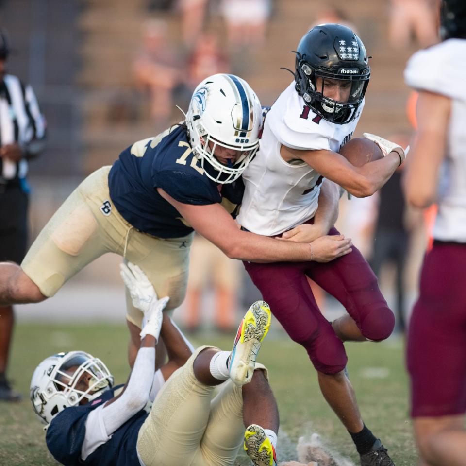 Trayvynn Ippolito (17) is taken down by Londen Taylor (72) as he carries the ball during the Navarre vs Gulf Breeze spring football game at Gulf Breeze High School on Friday, May 19, 2023.