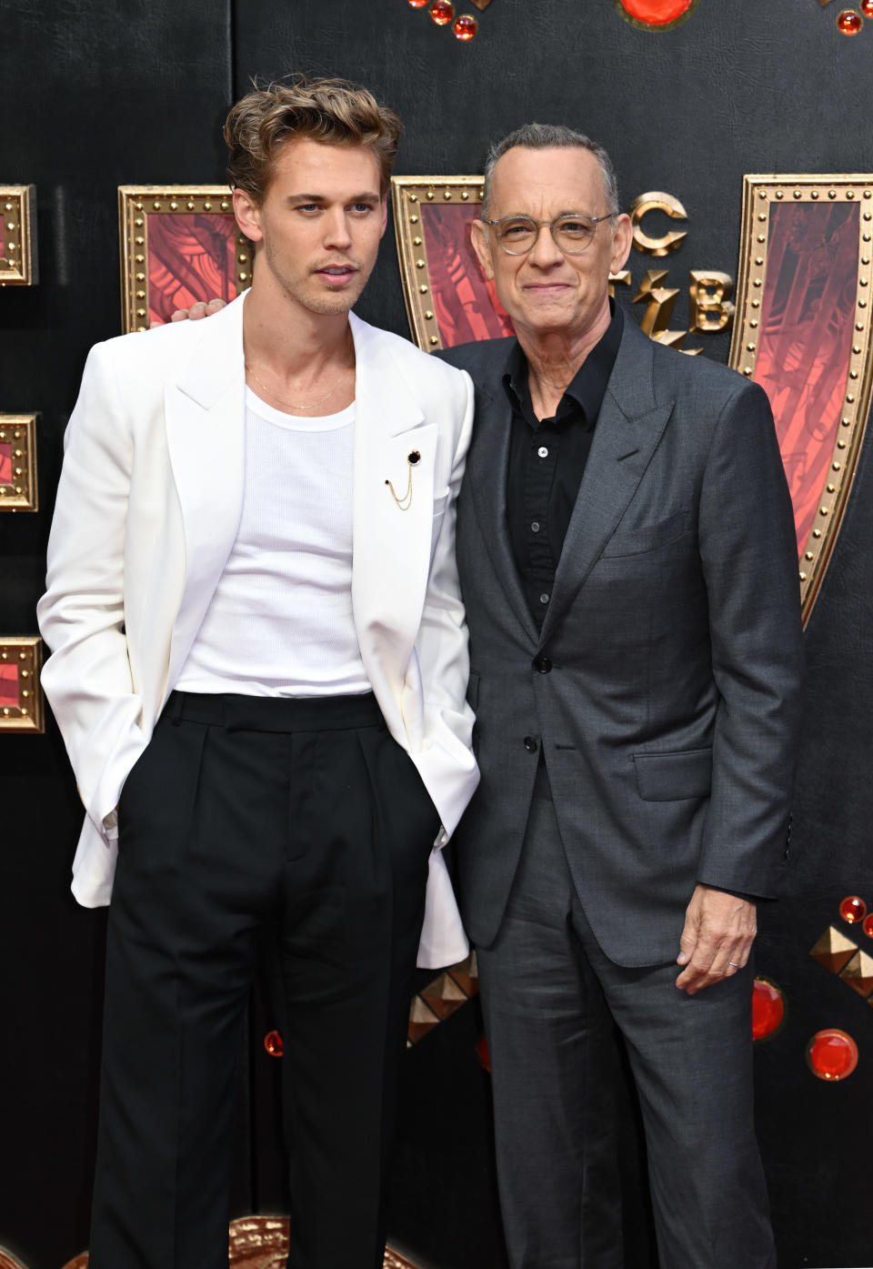 Closeup of Austin Butler and Tom Hanks smile for a photo together at a media event