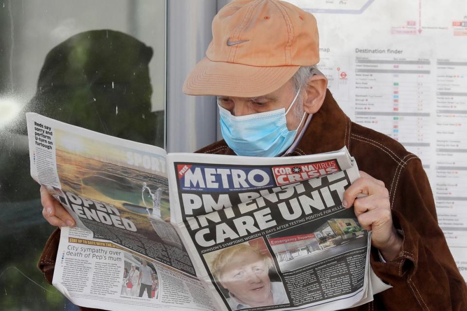 A man reads a newspaper with the front-page headline “PM in intensive care” outside a hospital  in London on April 7, 2020.  