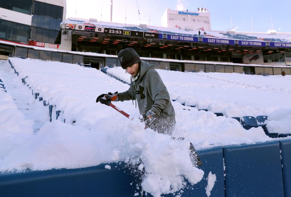 Gavin Weigand shovels snow from the lower bowl inside Highmark Stadium before the Buffalo Bills game.