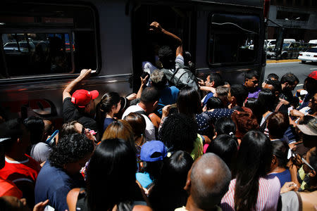People try to get on a bus outside a closed metro station during a blackout in Caracas, Venezuela March 25, 2019. REUTERS/Carlos Garcia Rawlins