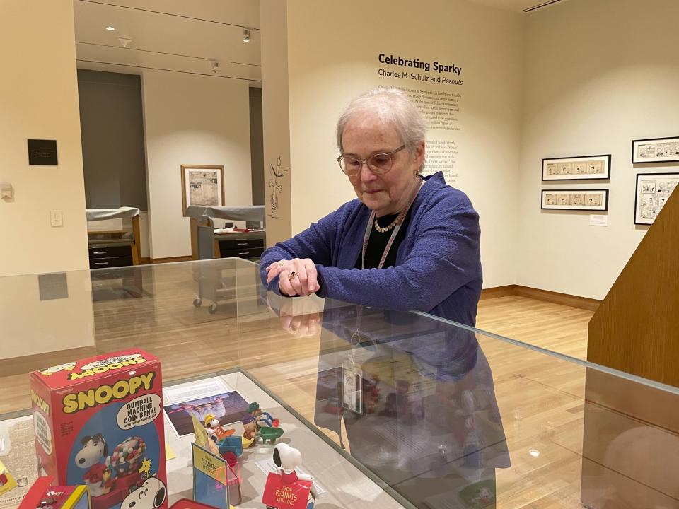 Lucy Shelton Caswell, founding curator of the Billy Ireland Cartoon Library Museum, examines memorabilia tied to the comic strip "Peanuts" on Friday, May 20, 2022, in Columbus, Ohio. Caswell curated a new exhibit, "Celebrating Sparky: Charles M. Schulz and Peanuts," one of a series of exhibits this year commemorating the centenary of the birth of Schulz. (AP Photo/Patrick Orsagos)