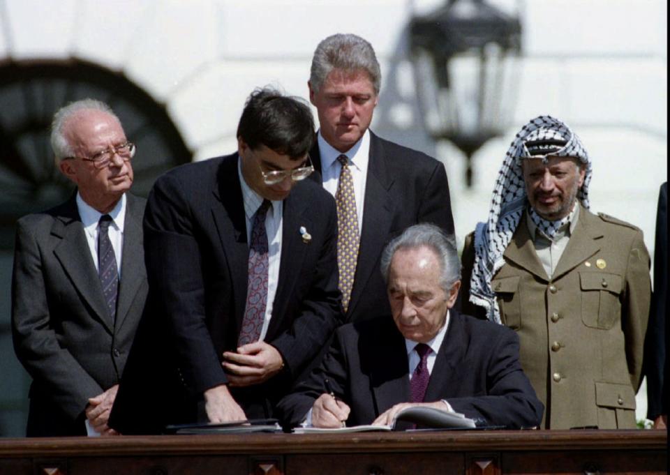 El Ministro de Exteriores israelí, Shimon Peres firma el acuerdo de paz alcanzado entre Israel y la Organización para la Liberación de Palestina (OLP) el 13 de septiembre de 1993, delante del primer ministro de Israel, Yitzhak Rabin (primero de la izquierda), el presidente de EEUU, Bill Clinton, y el presidente de la OLP Yasser Arafat (primero de la derecha). (Gary Hershorn/Reuters)