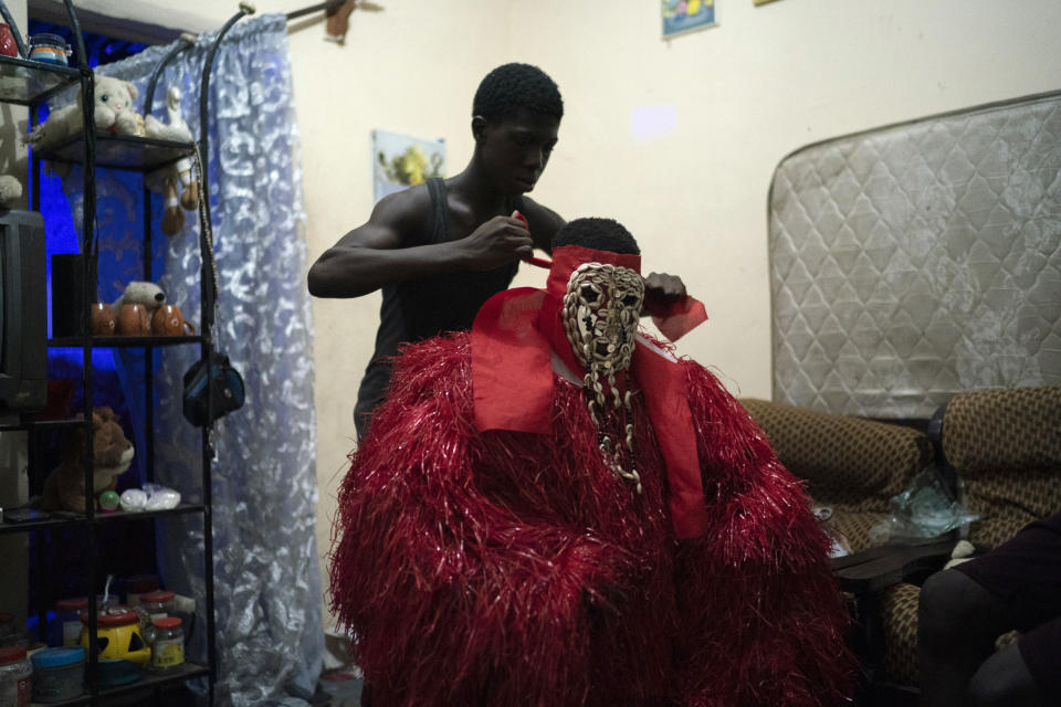 A man dressed as the Kankurang, has his mask tied before taking part in a ritual, in Bakau, Gambia, Friday, Oct. 1, 2021. The Kankurang rite was recognized in 2005 by UNESCO, which proclaimed it a cultural heritage. Despite his fearsome appearance, the Kankurang symbolizes the spirit that provides order and justice and is considered a protector against evil. He appears at ceremonies where circumcised boys are taught cultural practices, including discipline and respect. (AP Photo/Leo Correa)