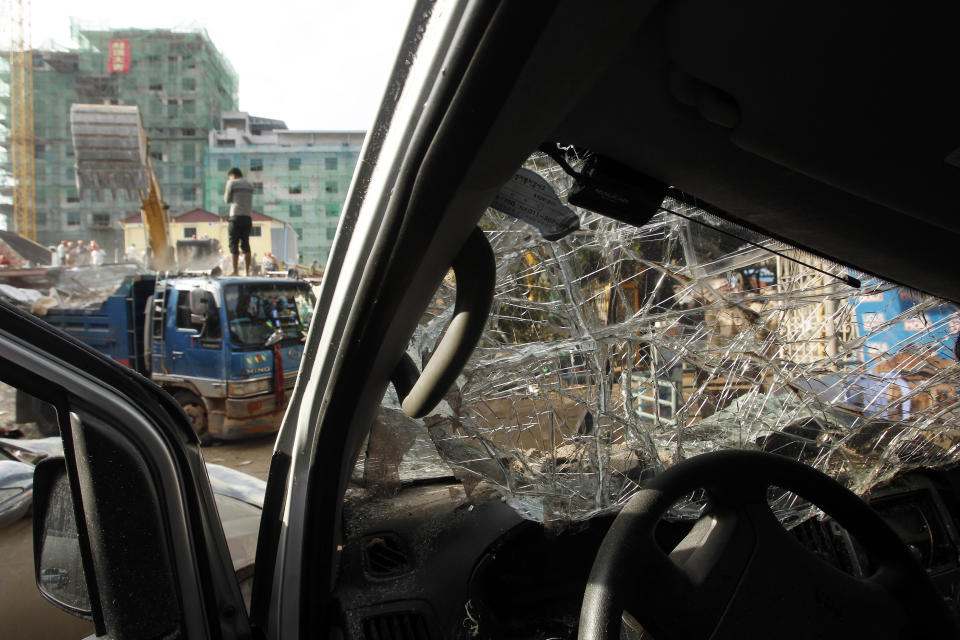 A car damaged by a building collapse sits near the site in Preah Sihanouk province, Cambodia, Sunday, June 23, 2019. Rescue workers were using saws to cut steel beams and excavators to move piles of rubble of the collapsed seven-story building. (AP Photo/Heng Sinith)