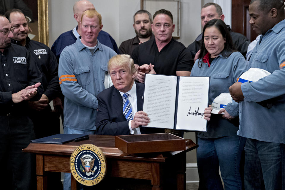 US President Donald Trump signs off an order to raise tariffs on steel imports surrounded by workers from the industry (Getty)