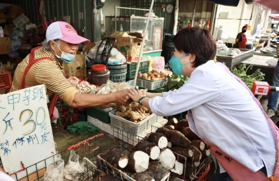 台中市長盧秀燕昨日一早到沙鹿市場掃街拜票，遇到削芋頭的阿伯，盧秀燕伸手緊握。（記者陳金龍攝）