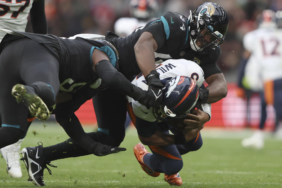 Denver Broncos quarterback Russell Wilson (3) is taken down by Jacksonville Jaguars linebacker Travon Walker (44), rear, during the NFL football game between Denver Broncos and Jacksonville Jaguars at Wembley Stadium in London, Sunday, Oct. 30, 2022. (AP Photo/Ian Walton)