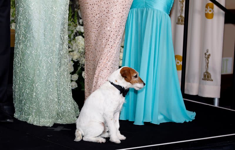 FILE PHOTO: Uggie, the dog from the best picture winning film "The Artist," poses onstage with cast members in the photo room backstage at the 84th Academy Awards in Hollywood
