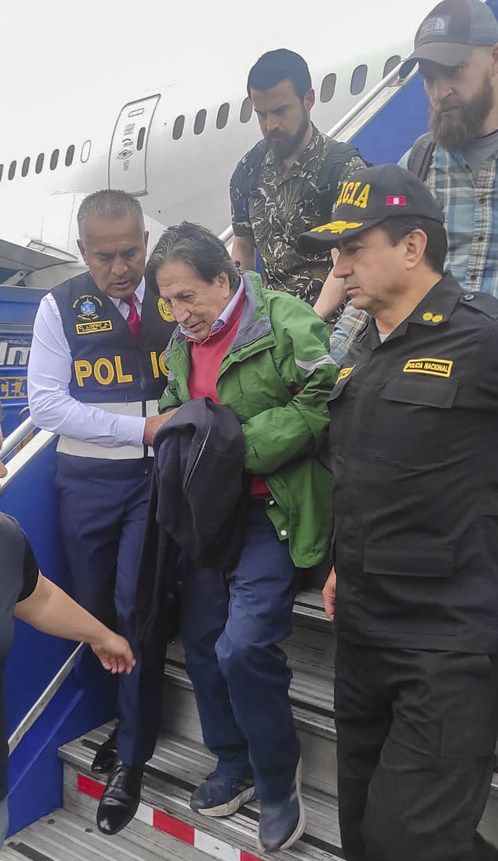 En esta foto difundida por la Policía Nacional de Perú, agentes escoltan al expresidente Alejandro Toledo tras su llegada extraditado desde Estados Unidos, al aeropuerto de Lima, el domingo 23 de abril de 2023. (Policía Nacional de Perú, vía AP)