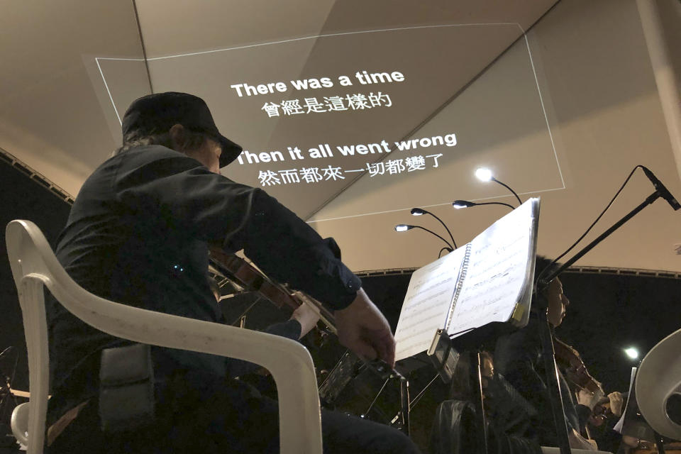 In this Tuesday, Dec. 10, 2019 photo, lyrics are projected on a canopy as a theater troupe performs Les Miserables in at an outdoor event space in Hong Kong. A Hong Kong theater troupe is making audiences weep by touring a stirring production of 'Les Miserables.' Based on Victor Hugo's tale of rebellion in 19th-century France, the rousing music and lyrics of struggle and resistance struck chords with audience members emotionally and physically drained after six months of protests that have convulsed the city. (AP Photo/John Leicester)