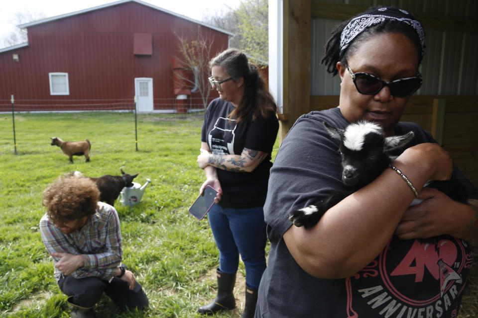 Pamela Merritt, right, holds a baby goat, accompanied by Alison Dreith and Jake McDaniel at the couple's farm in southern Illinois on Tuesday, April 12, 2022. Both women have worked for years on reproductive rights and are part of a network of people who vow to maintain access to abortion, even as more states restrict that access. Merritt says, "We've been through so much together, politically, professionally and personally." (AP Photo/Martha Irvine)