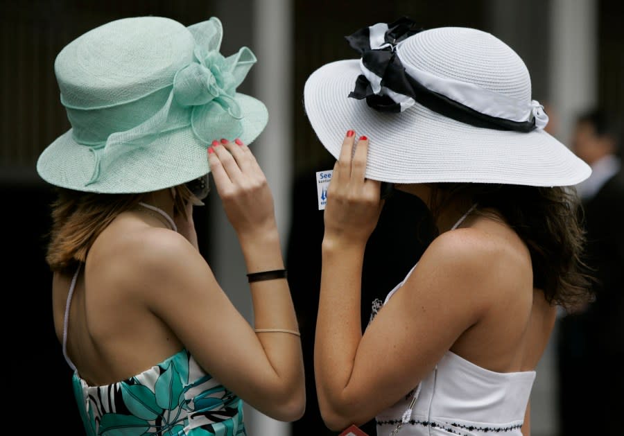 FILE – Shelby Wilkes, left, and Pam Deegan, both of Louisville, Ky., holds their hats from the wind during the 134th Kentucky Derby Saturday, May 3, 2008, at Churchill Downs in Louisville, Ky. The first Saturday in May is Derby Day with all its accompanying pageantry, including fancy hats. (AP Photo/Amy Sancetta, File)