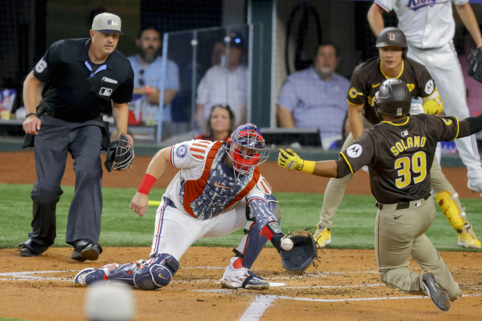 Texas Rangers catcher Andrew Knizner, bottom center, receives a throw from left fielder Wyatt Langford and tags San Diego Padres' Donovan Solano (39) out at home plate during the fourth inning of a baseball game Thursday, July 4, 2024, in Arlington, Texas. (AP Photo/Gareth Patterson)