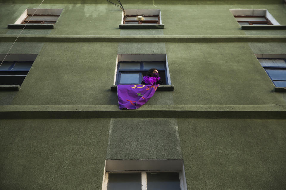 A woman holds a support banner from a window as protesters march to mark International Women's Day in Istanbul, Monday, March 8, 2021.Thousands of people joined the march to denounce violence against women in Turkey, where more than 400 women were killed last year. The demonstrators are demanding strong measures to stop attacks on women by former partners or family members as well as government commitment to a European treaty on combatting violence against women. (AP Photo/Emrah Gurel)