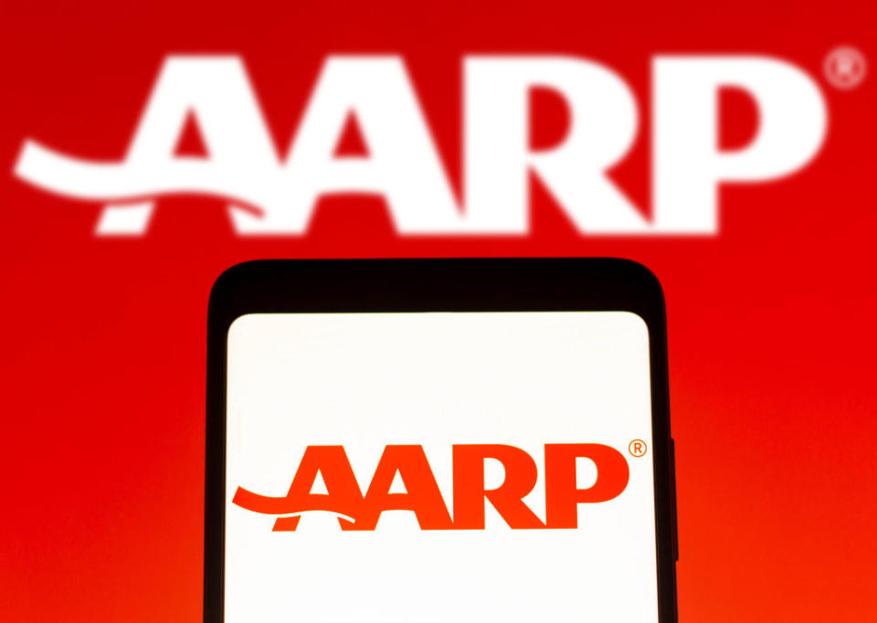 AARP logo is displayed on a smartphone screen with a larger AARP logo in the background