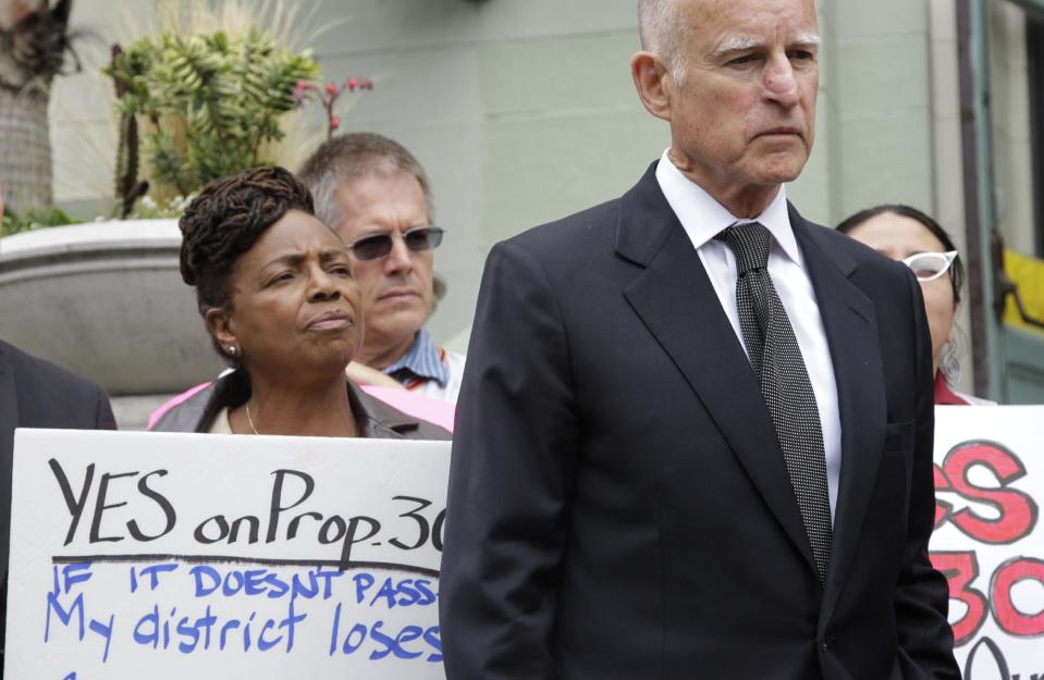 Calif. Gov. Jerry Brown listens to other speakers as he campaigns supporting Proposition 30 at James Lick Middle School in San Francisco, Wednesday, Aug. 22, 2012. As Brown kicked off his campaign for Proposition 30 last week, he sought to emphasize that most of the revenue from the tax increases would come from Californians who are among the wealthiest; an extra $4,500 a year for millionaires, he said. (AP Photo/Paul Sakuma)