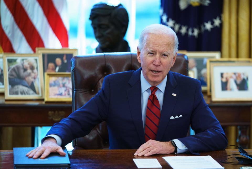 President Biden speaks as he holds his hand on a blue volume.