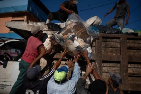 Men help move trash left by thousands of migrants from Central America, who are en route to the United States, in Huixtla, Mexico October 23, 2018. REUTERS/Adrees Latif