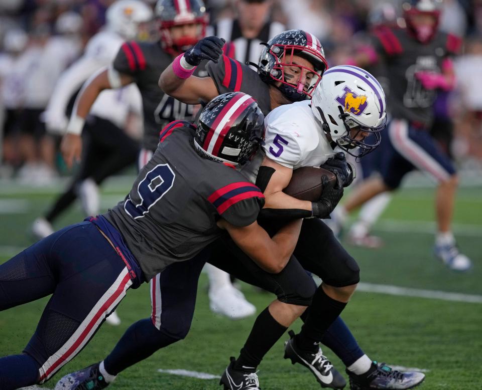 DeSales' Bryce Herrick is tackled by Hartley's Joey Wooten (9) and Rory Ralston (43) during Friday night's game at Hartley. The host Hawks won the CCL contest 15-12.