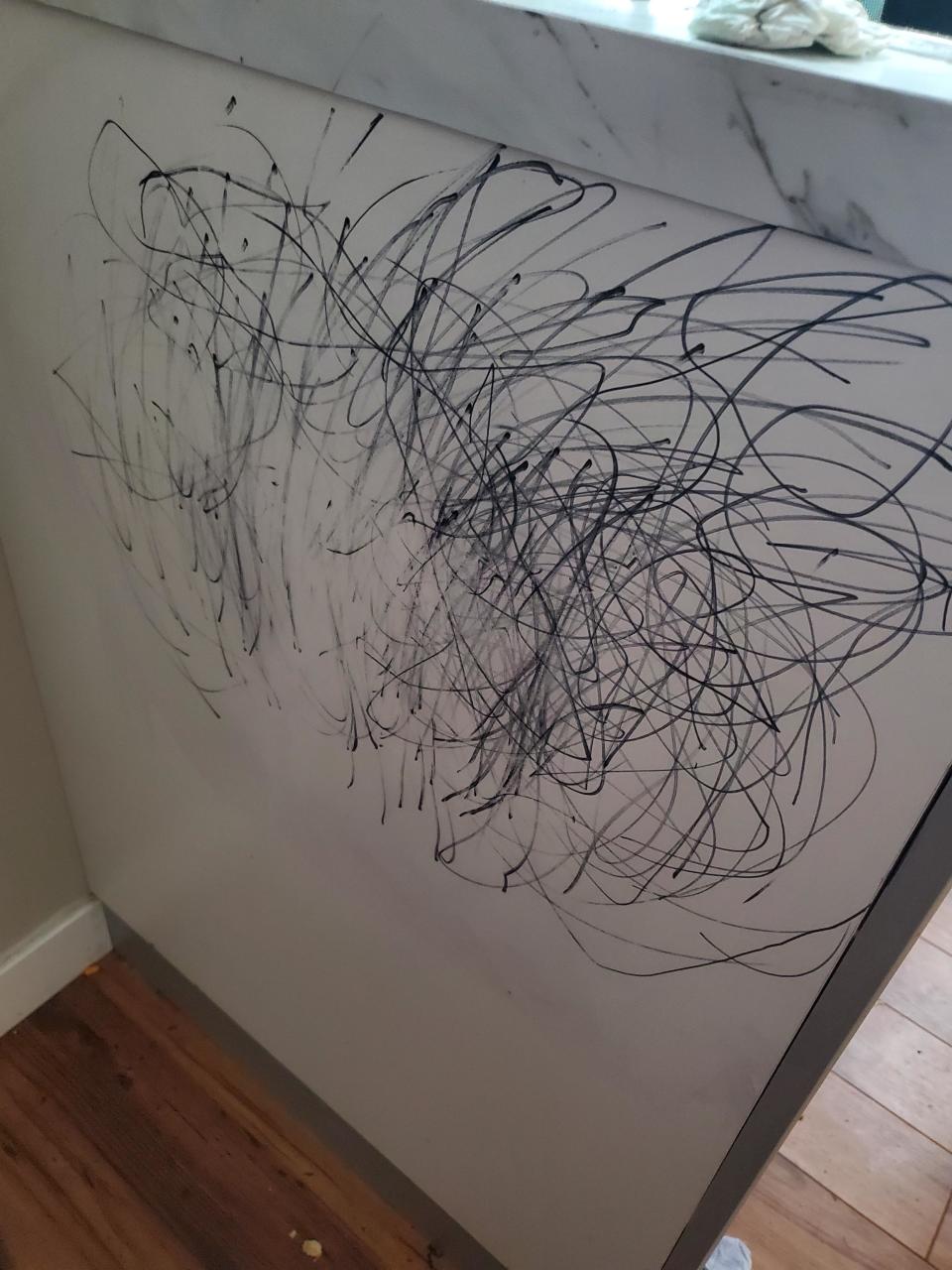 Scratches and scribbles cover a white surface, implying a child's drawing or accidental marks