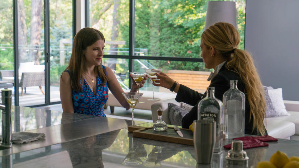 Anna and Blake raise a glass in a toast in a brightly lit room with modern decor