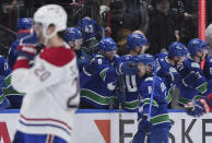 Vancouver Canucks' Conor Garland (8) catches the glove of J.T. Miller (9) in the face as he skates past the bench to celebrate his goal against the Montreal Canadiens during the second period of an NHL hockey game Thursday, March 21, 2024, in Vancouver, British Columbia. (Darryl Dyck/The Canadian Press via AP)